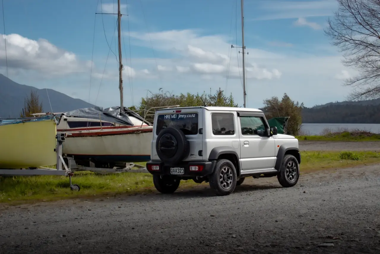 Suzuki Jimny in forest or scenic road setting. – Jimny Rentals.