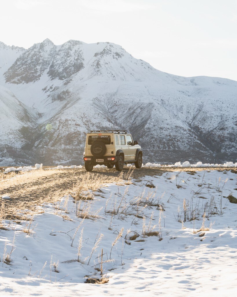 Jimny driving through ice-walled mountain road at dusk