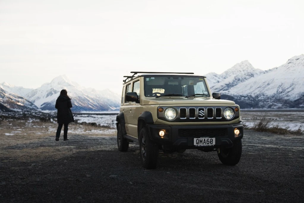 Suzuki Jimny with lights on in a snowy South Island alpine landscape